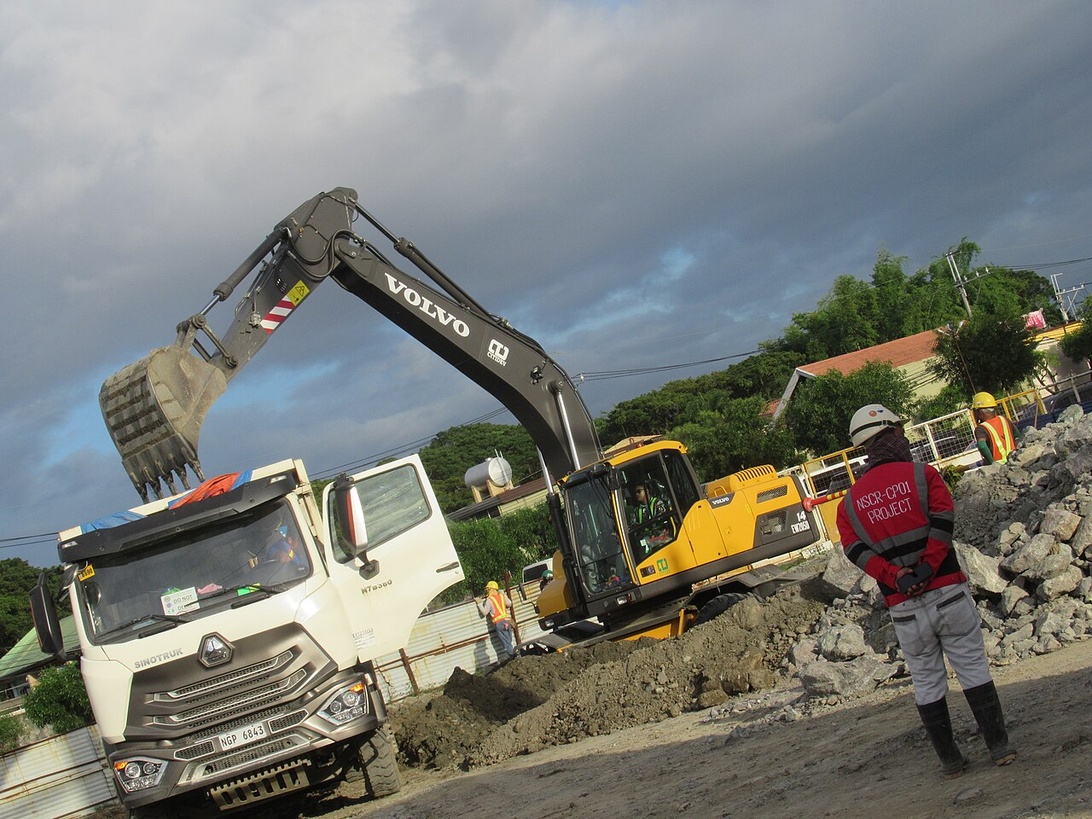 Ein historischer dampfbetriebener Bagger auf Schienen bei der Arbeit.