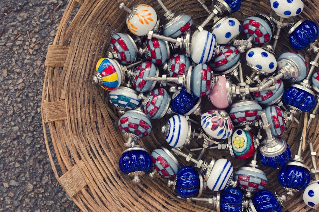 Bunt verzierte Möbelknöpfe aus Keramik in einem geflochtenen Weidenkorb.