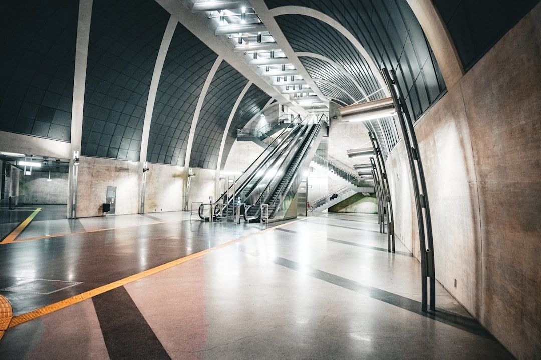 Leere, modern gestaltete Bahnhofshalle mit Rolltreppen und taktilen Leitlinien