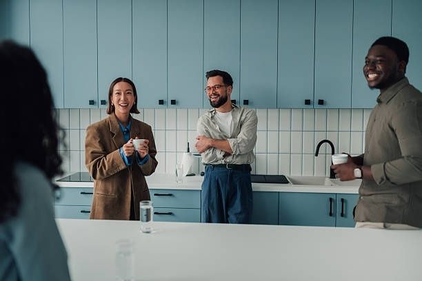 Kolleginnen und Kollegen unterhalten sich bei einer Kaffeepause in der Büroküche